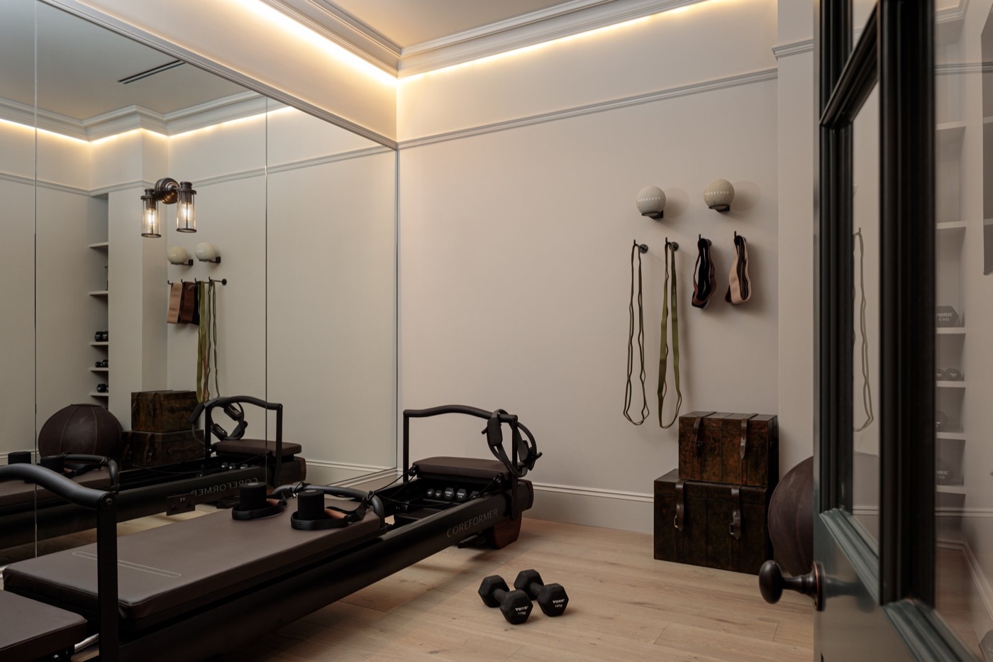 A basement room fitted out for reformer Pilates, with a mirrored wall